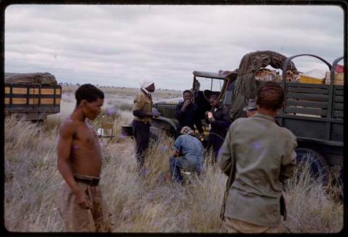 Expedition members and other people in tall grass by an expedition truck