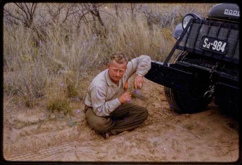 Theunis Berger sitting on ground by Expedition truck