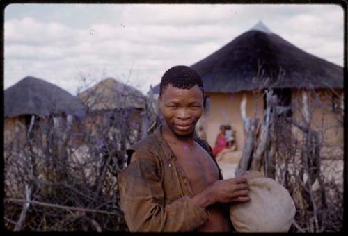 Young man standing in front of gate, village in background