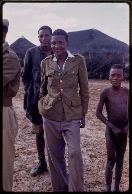 Group of people standing, a boy wearing an army coat