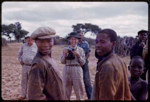 Group of people standing, Lorna Marshall standing behind with a camera