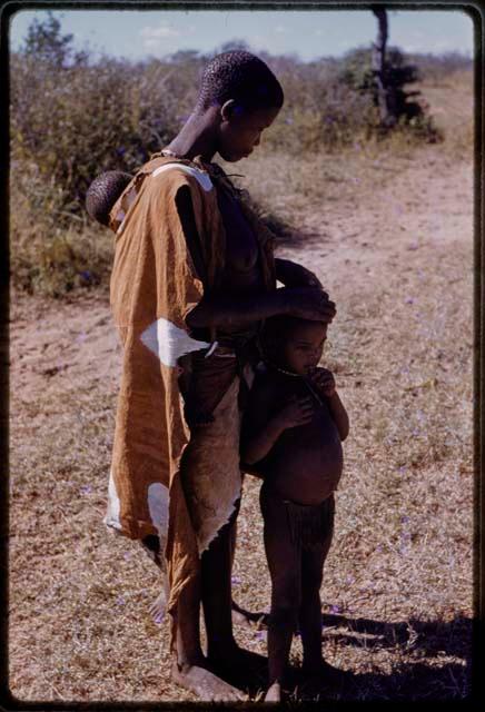 Woman carrying a baby and resting her hands on a child's head