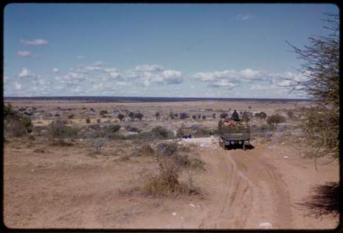 Expedition trucks driving into a valley, seen from behind