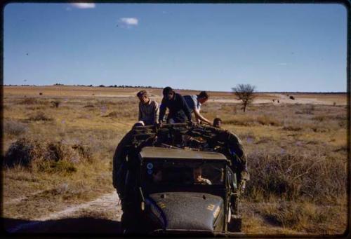 Expedition truck driving, expedition members sitting on top