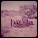 Dance: Men dancing in a line through a circle of women sitting, view from the top of an expedition truck