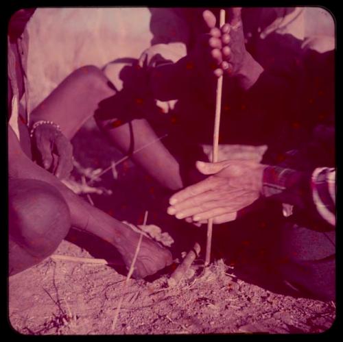 Fire-Making: Person helping Lorna Marshall use a fire stick, close-up of hands