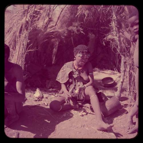 Food, Eating: //Kushay sitting in front of a skerm, eating veldkos, with a wooden bowl and mortar on the ground next to her