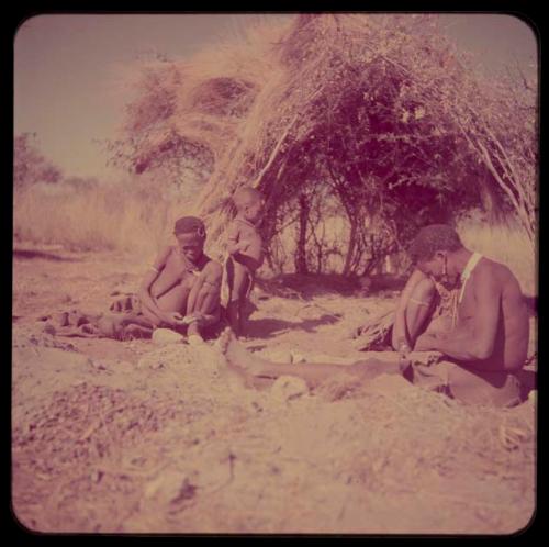 Groups, "Nuclear Family": Khuan//a (Gau's second wife) sitting in front of a skerm with another person, a visitor