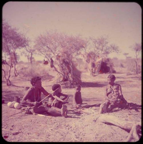 Groups, "Nuclear Family": ≠Toma working on arrows and sitting with his family, including Tsamgao, /Gaishay and !U, who is holding !Ungka Norna on her lap