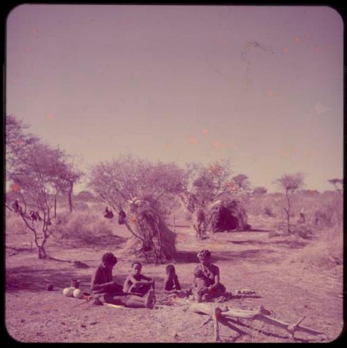 Groups, "Nuclear Family": ≠Toma working on arrows and sitting with his family, including Tsamgao, /Gaishay and !U, who is holding !Ungka Norna on her lap, distant view