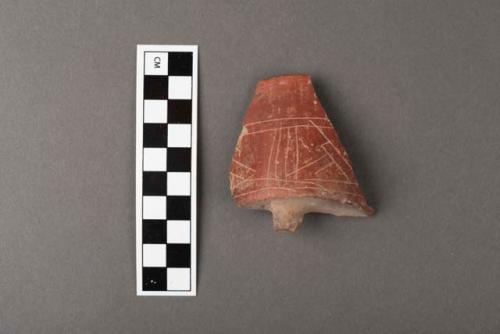 Fragment of small red incised straight -sided flat-bottomed pottery tripod bowl