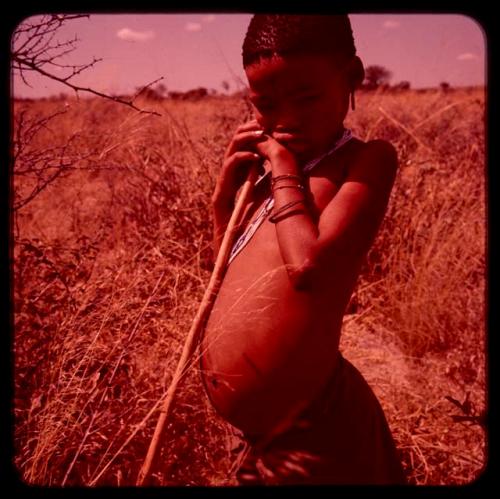 Boy standing, leaning on a digging stick to gather food