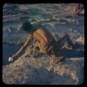 Boy scooping pan water into a cup, seen from behind