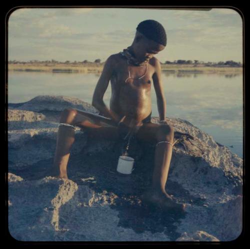 Boy sitting by pan and urinating into a cup