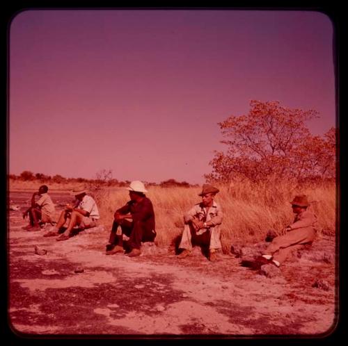 Expedition members sitting in a row on pan's shore