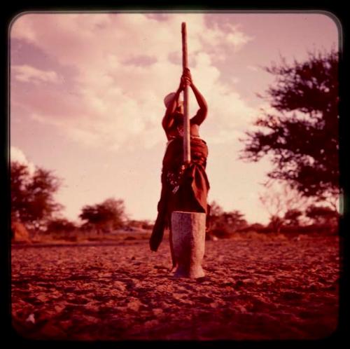 Woman pounding something in a large mortar