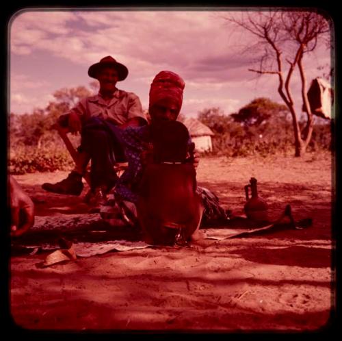 Venter's (Fendare) wife sitting and facing a child, with a man sitting in a chair and watching them in the background