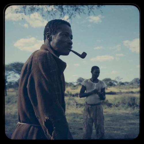 Man with a pipe in his mouth and another man standing in the background at Venter’s (Fendare) property