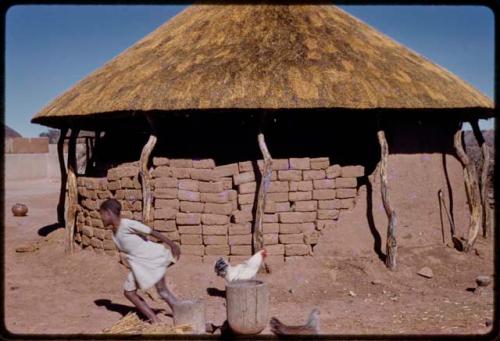 House under construction, shows bricks, child and chickens in front