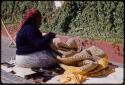 Woman sitting, sewing a quilt