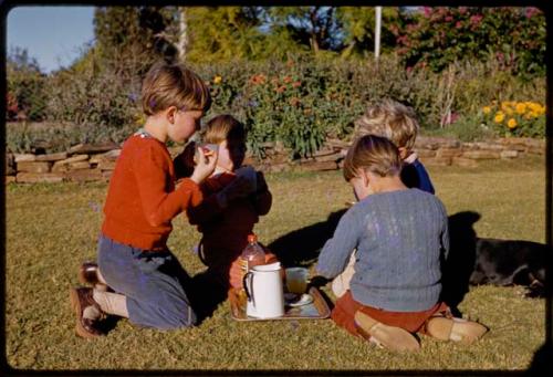 Grant family children sitting in a yard and drinking tea