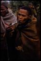 Man smoking a pipe, other people in the background