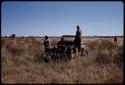 John Marshall taking a photo, Elizabeth Marshall Thomas and Theunis Berger sitting in the expedition Jeep