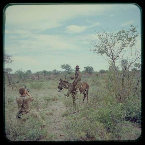 John Marshall taking a photo of a man riding on a donkey