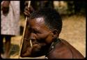 Man sitting, holding a stick, profile