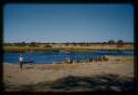 People standing and sitting along the Okavango River, with fish traps on the ground next to them