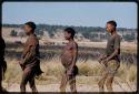 Three men standing in line, waiting to be paid by Mr. Kruger for work on a fire break, close-up, with burned strip in the background