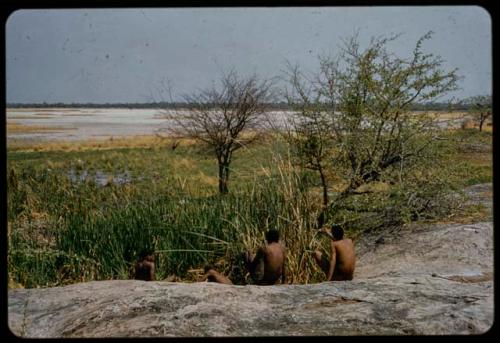 Four men sitting next to the Gautscha waterhole, with Gautscha Pan in the background