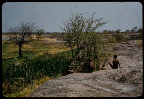 Three men sitting next to the Gautscha waterhole, with Gautscha Pan in the background