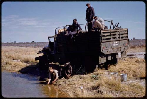 Expedition members pumping water into water drums in a truck