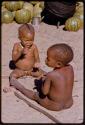 Two children with digging sticks, sitting