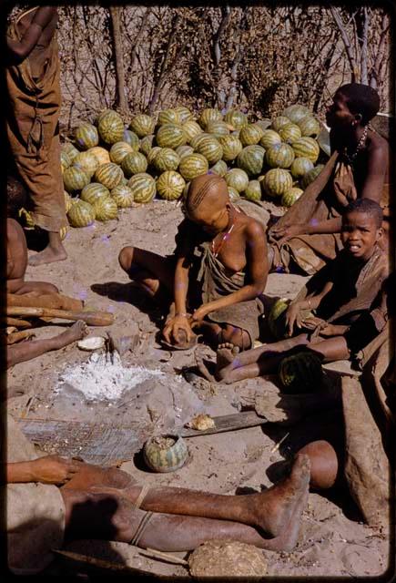 Woman making snuff, people sitting near her