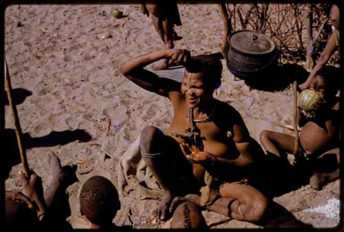 Woman squeezing pulp of water root into her mouth, people sitting around her