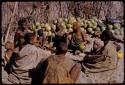 People sitting together by a pile of melons