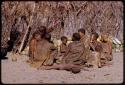 People sitting together by a pile of melons