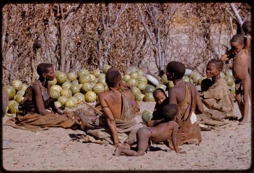 People sitting together by a pile of melons