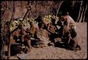 People sitting together by a pile of melons, John Marshall kneeling down beside them