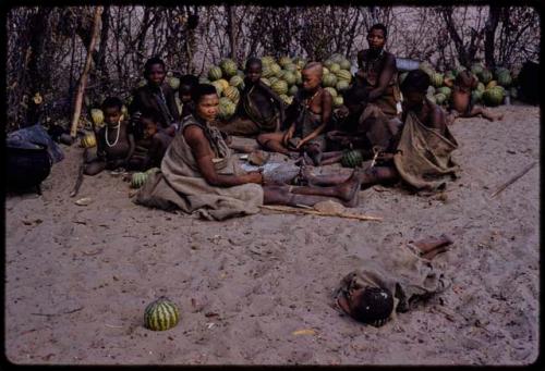 People sitting together by a pile of melons