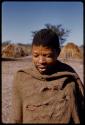 Man standing with huts in the background, close-up