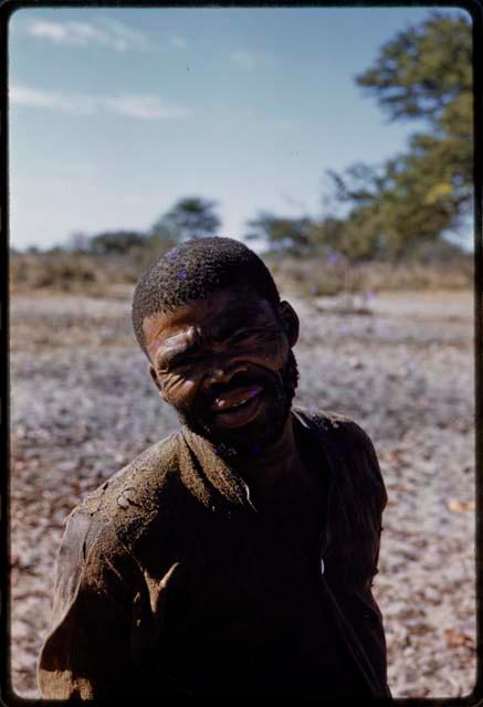 Man standing with huts in the background, close-up