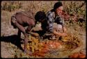 Oukwane dipping a tsama rind in gemsbok rumen liquid, John Marshall helping