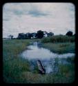 Okavango River fork and dugout, with a man riding in a boat from a distance