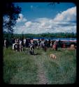 Group of people, including the expedition members, gathered near a barge at the bank of the Okavango River