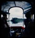 C.J. Mathias and Elizabeth Marshall Thomas sitting in a barge on the Okavango River, seen from behind