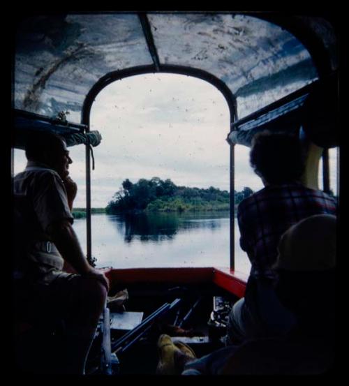 C.J. Mathias and Elizabeth Marshall Thomas sitting in a barge on the Kavango River, seen from behind