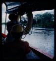 Elizabeth Marshall Thomas and Anneliese Scherz riding in a barge on the Okavango River, seen from behind